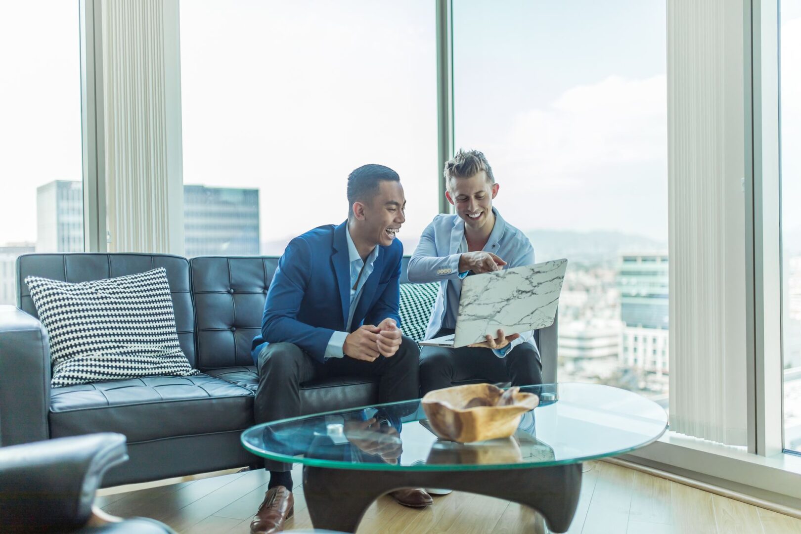 Two men sitting on a couch looking at something.