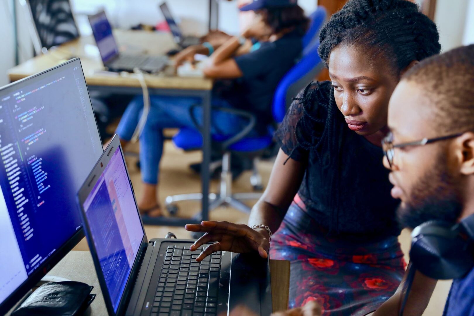 Two women are using a laptop in an office.