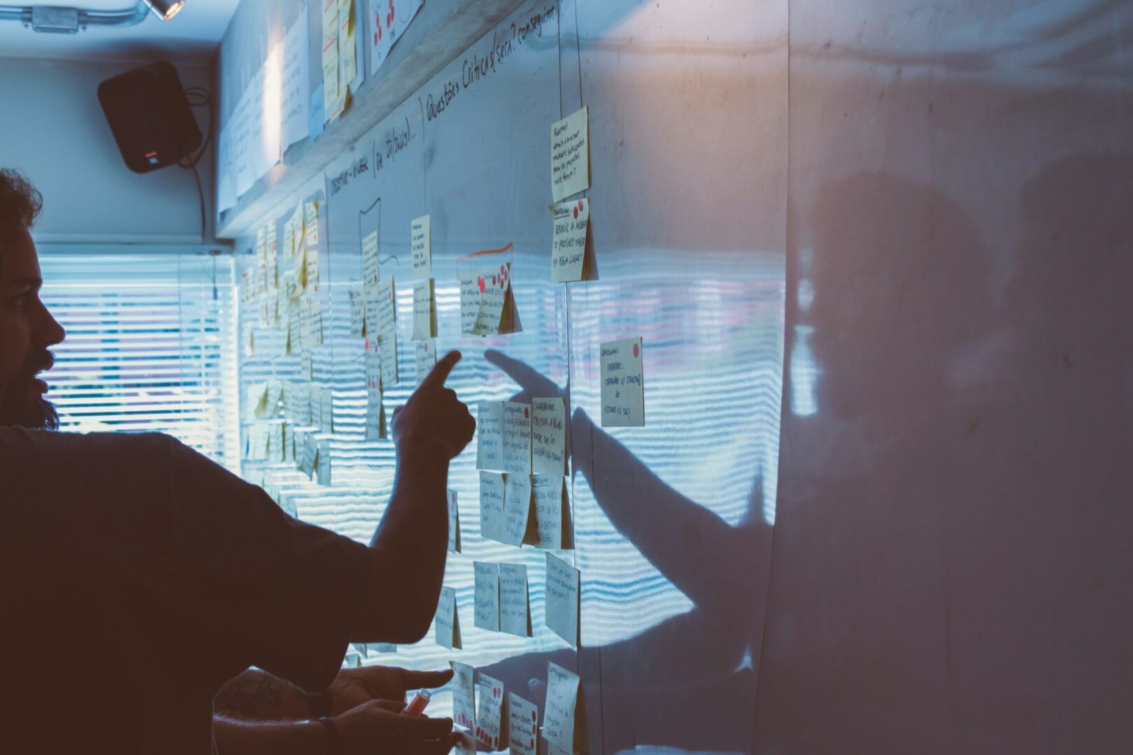 A person is looking at sticky notes on the wall.