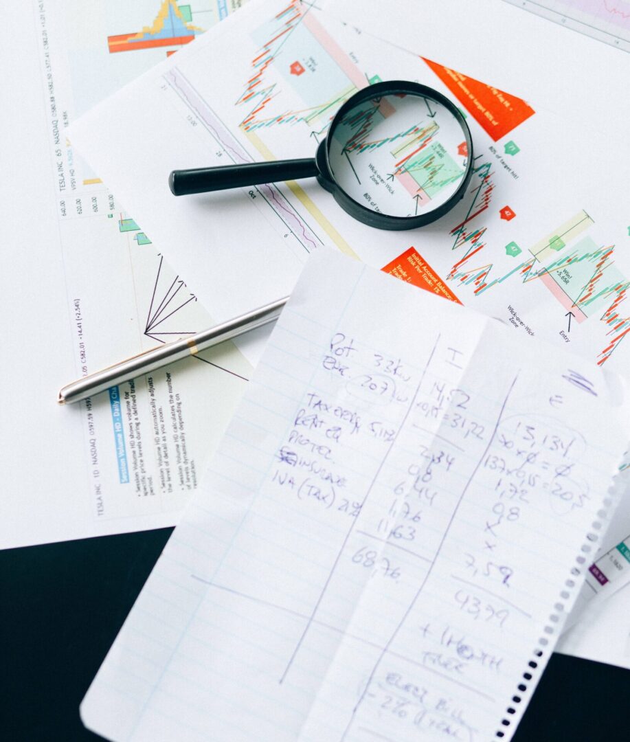 A pen, magnifying glass and paper are on the table.